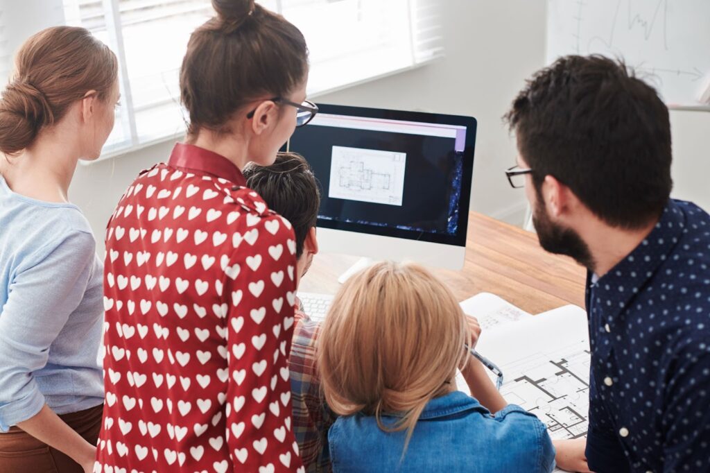 A team of individuals focused on a computer screen